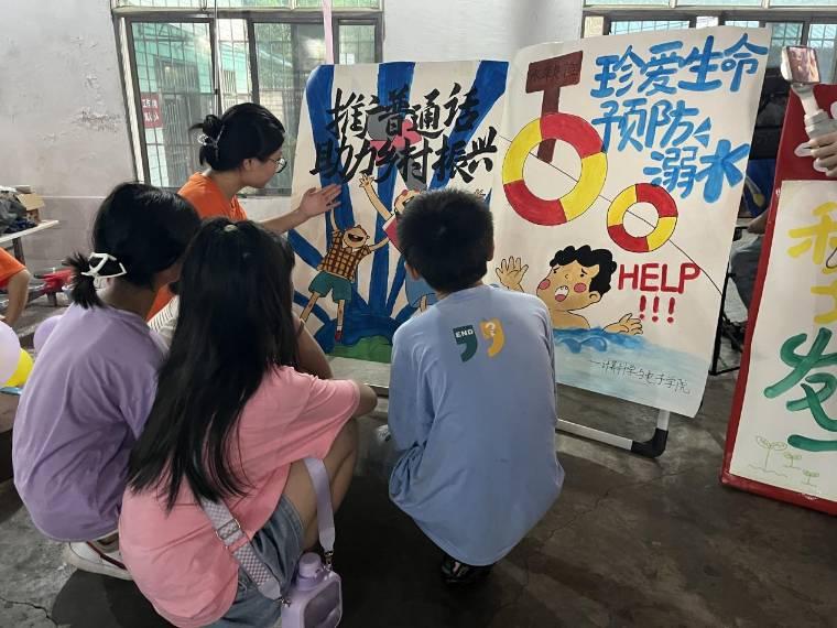 图为实践团成员教小朋友绘画推广普通话海报。龚艳星 摄